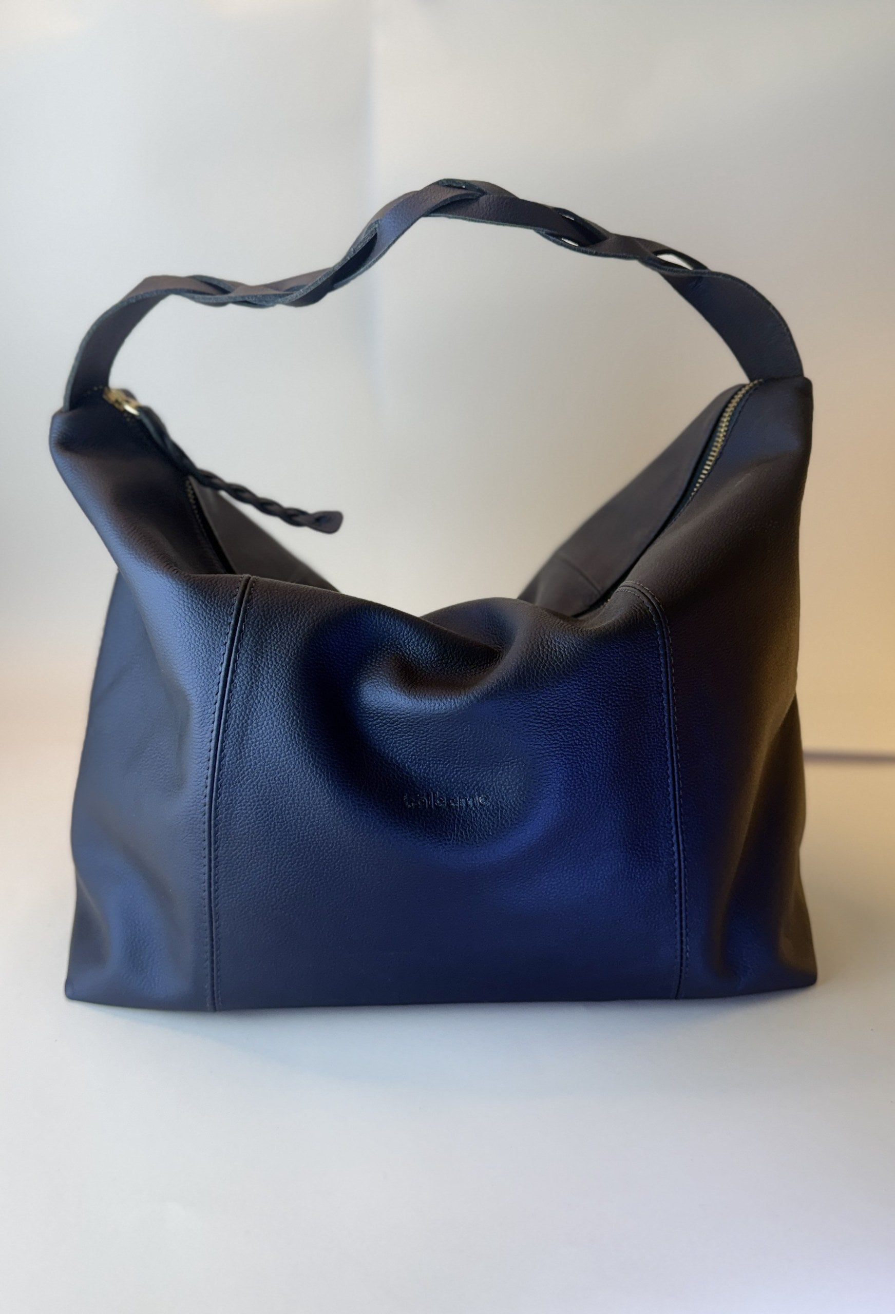 Bolso Trenza en cuero azul, con la manija trenzada sobre el bolso