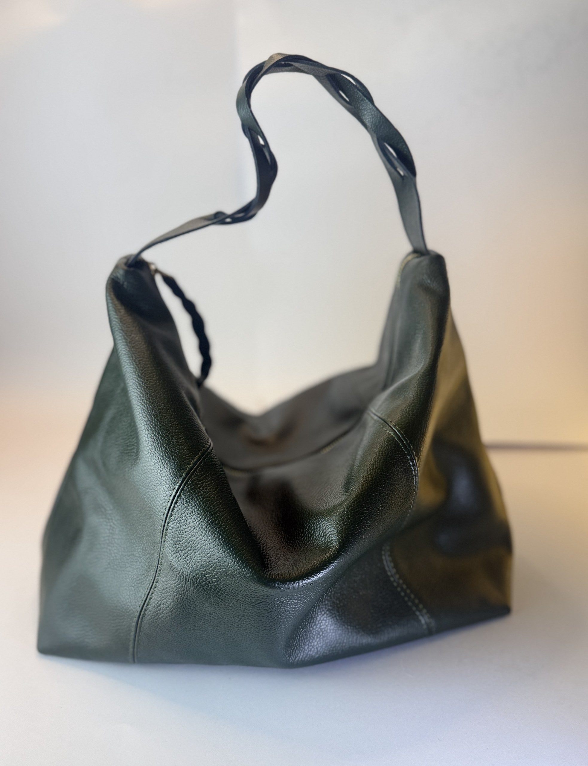 Bolso Trenza en cuero verde oscuro, con la manija trenzada sobre el bolso