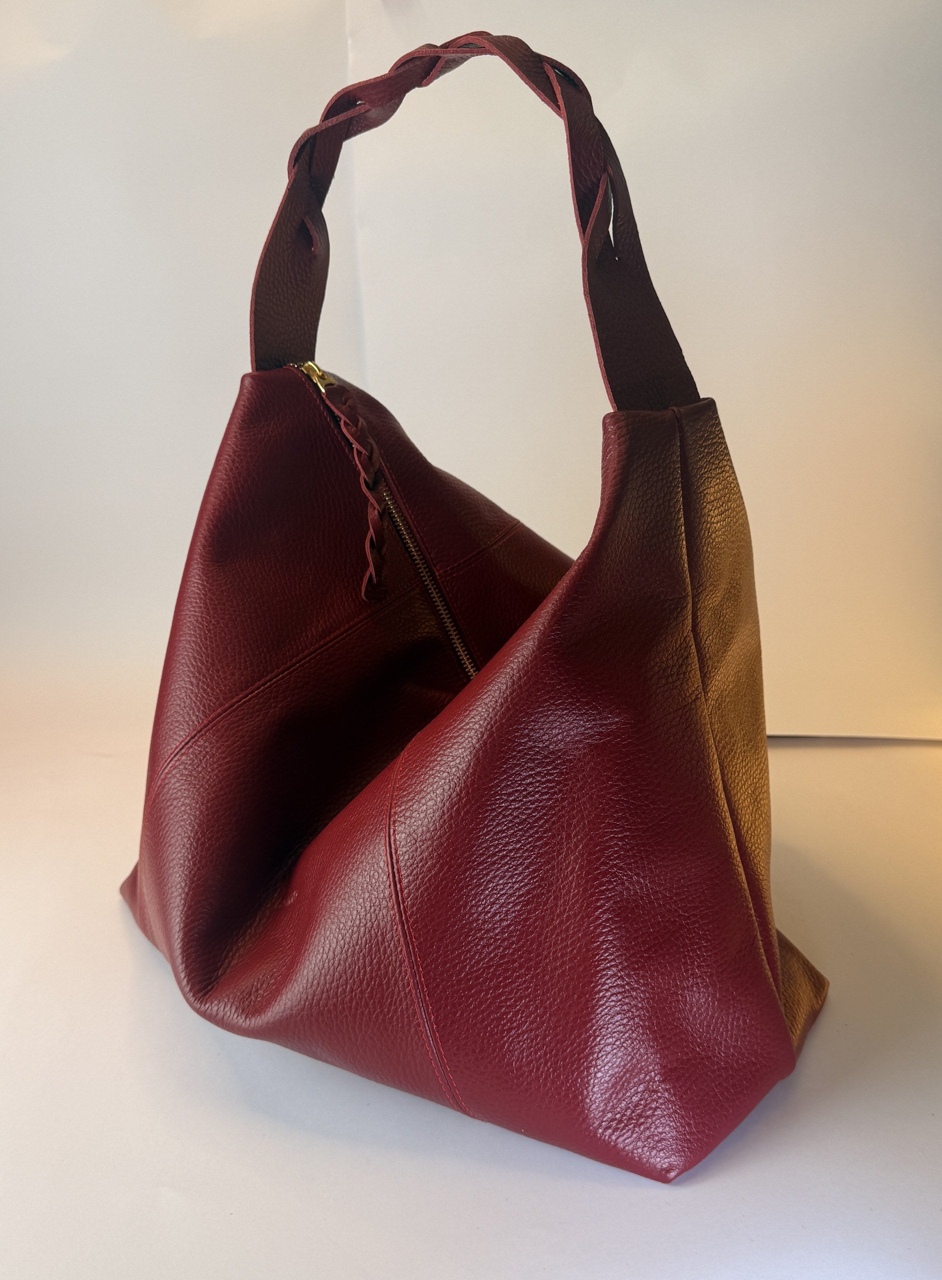 Bolso Trenza en cuero vino tinto, vista en tres cuartos con la manija trenzada
